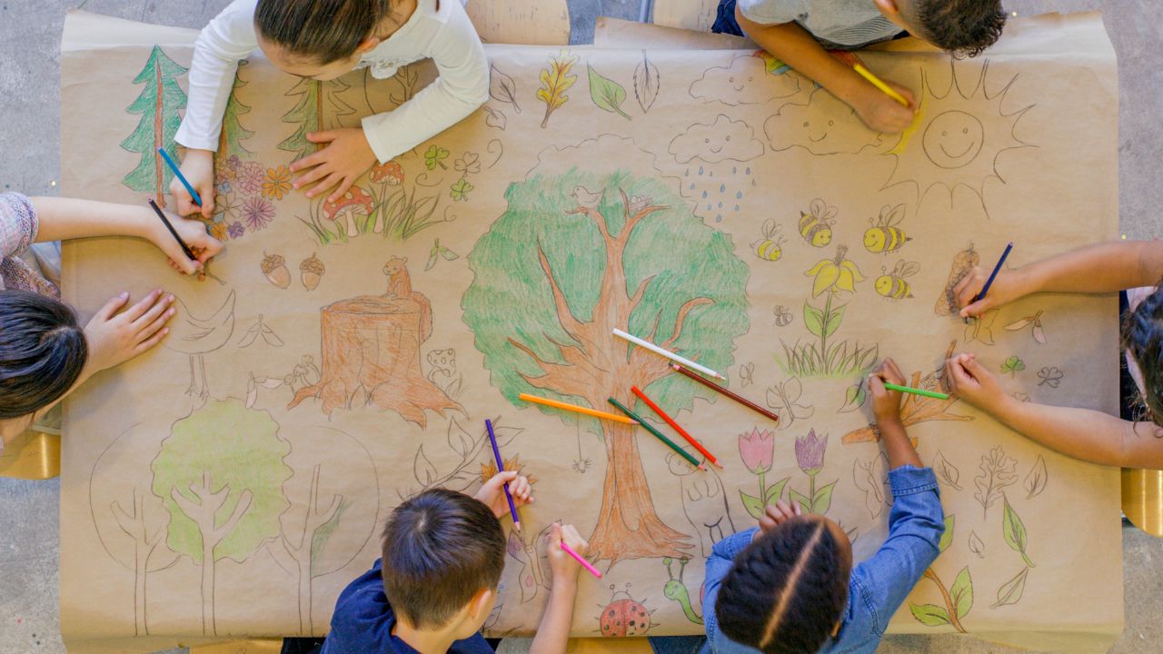 children coloring on a large piece of paper