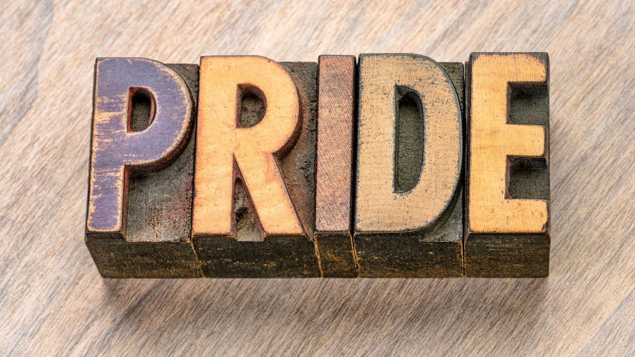 The word 'Pride' carved in a block of wood.