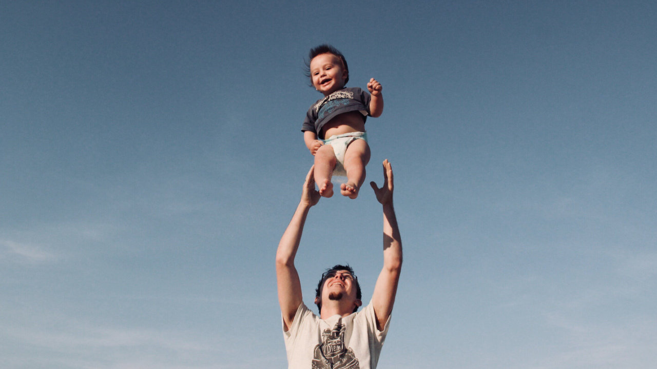 A man tossing a joyful, happy baby into the air and catching him.